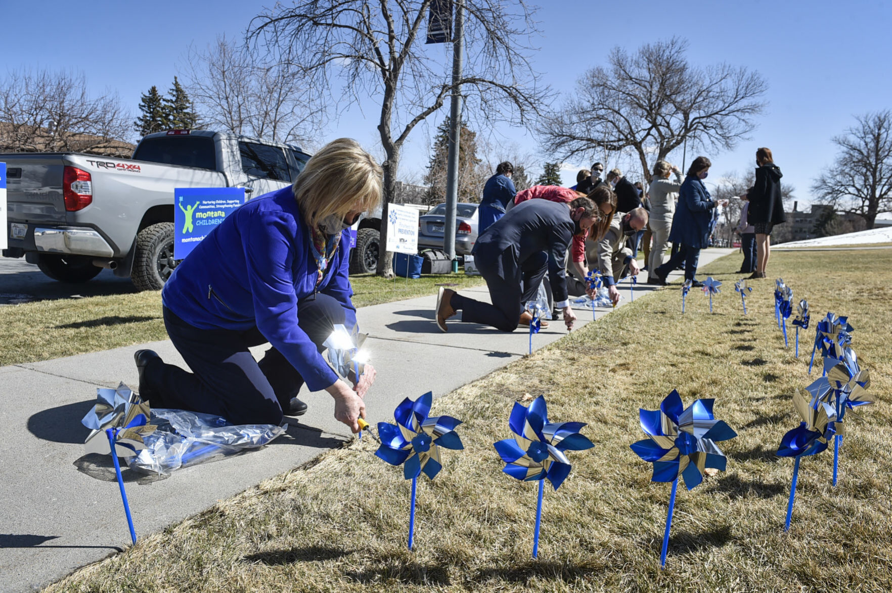 Lt. Gov. Kristen Juras, left, places a pinwheel in the ground